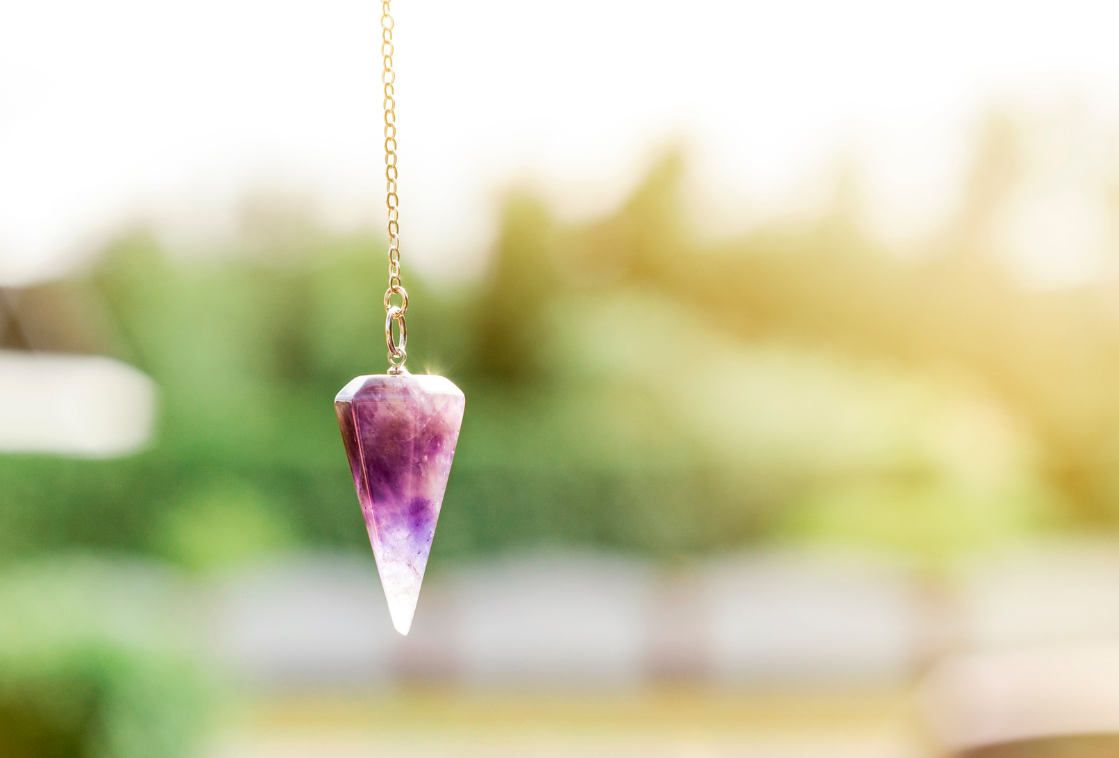 Amethyst crystal quartz pendulum hanging on chain.